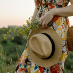 Frau im sommerlichen Leinen-Outfit mit Strohhut bei Sonnenuntergang