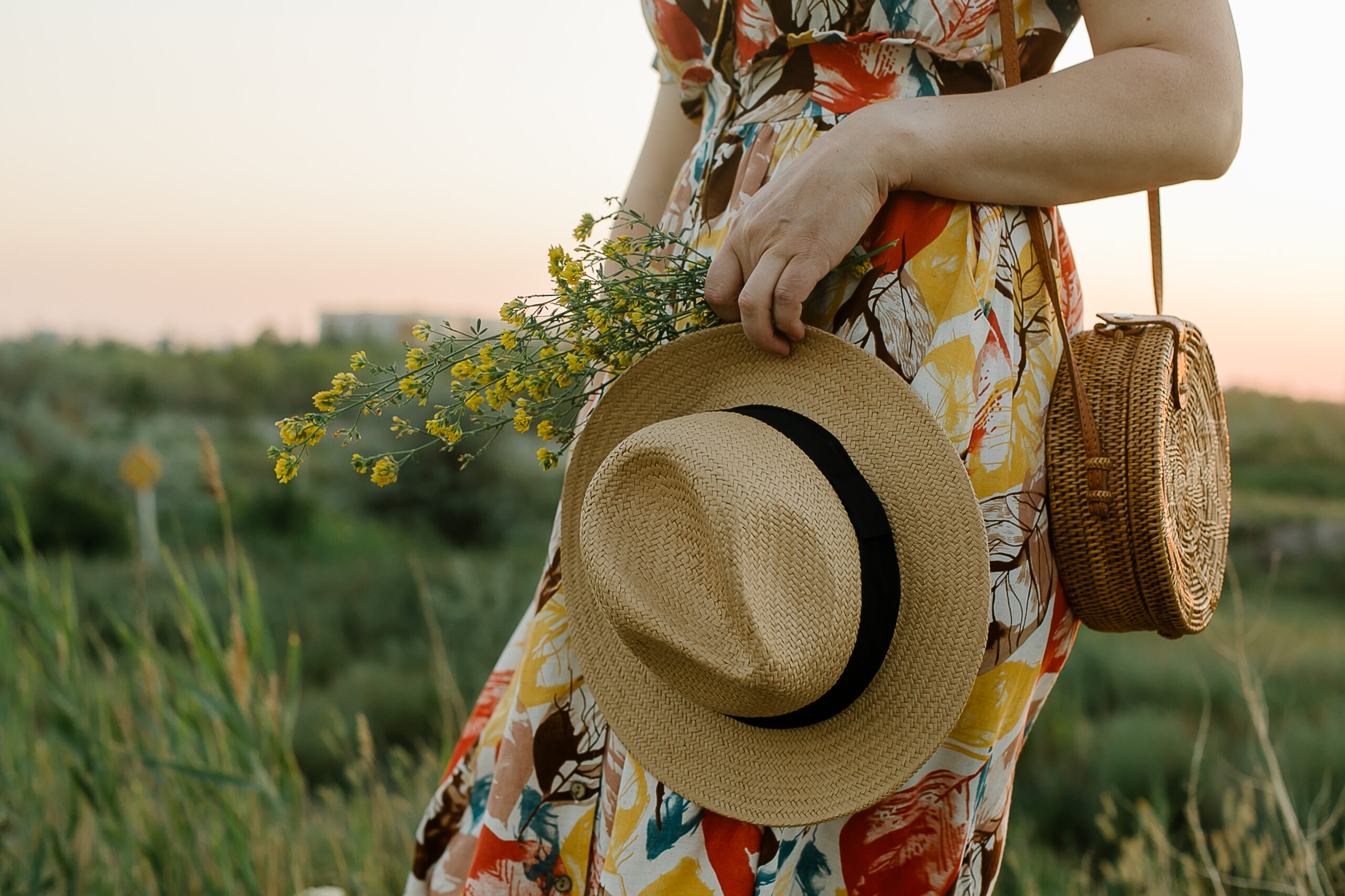 Frau im sommerlichen Leinen-Outfit mit Strohhut bei Sonnenuntergang