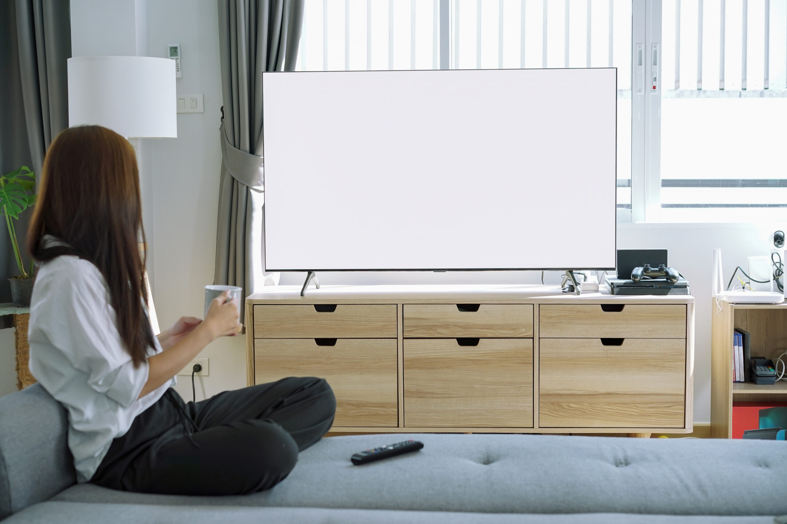 Frau entspannt auf dem Sofa und schaut Streaming im Fernsehen