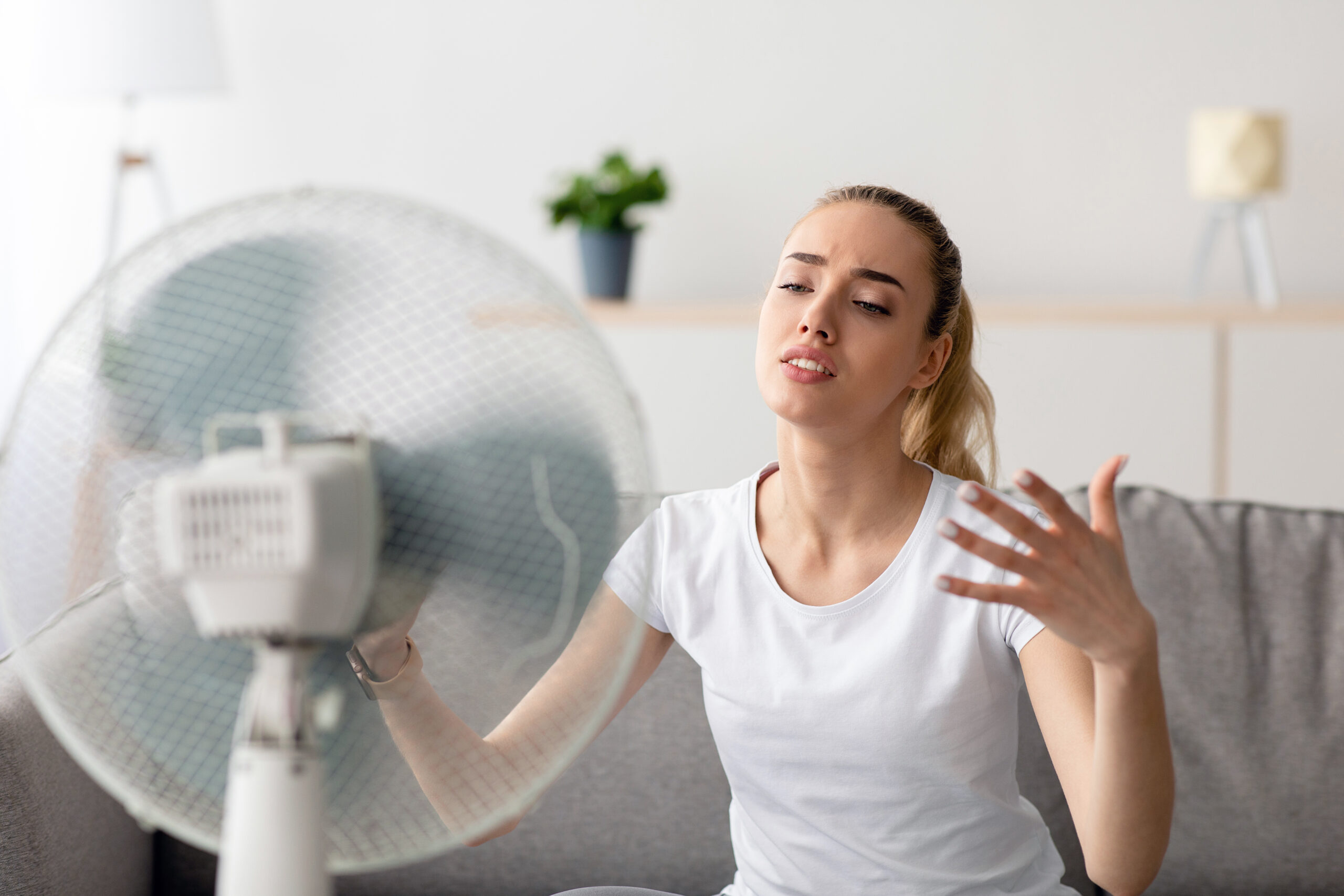 Frau kühlt sich bei einer Hitzewallung vor einem Ventilator ab